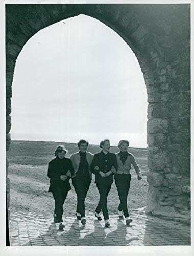 תצלום וינטג 'של כמה חברים הולכים זרוע לזרוע דרך אחת מקשתות הקיר בוויסבי